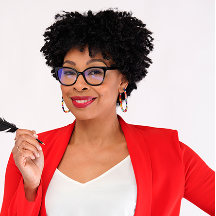A woman with mid-length curly heair and glasses holding a feather pen